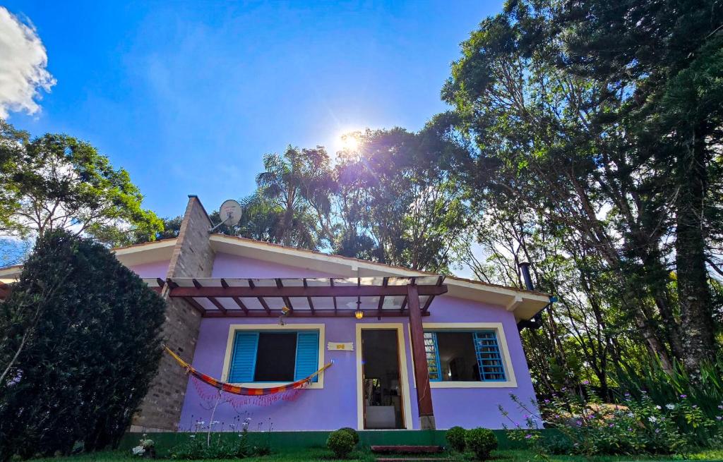 una casa rosa con alberi sullo sfondo di Villa das Águas a Monte Alegre do Sul