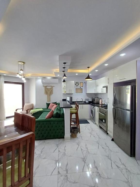 a living room with a green couch and a kitchen at شالية غرفتين و صالة ببورتوسعيد Family ONLY in Port Said
