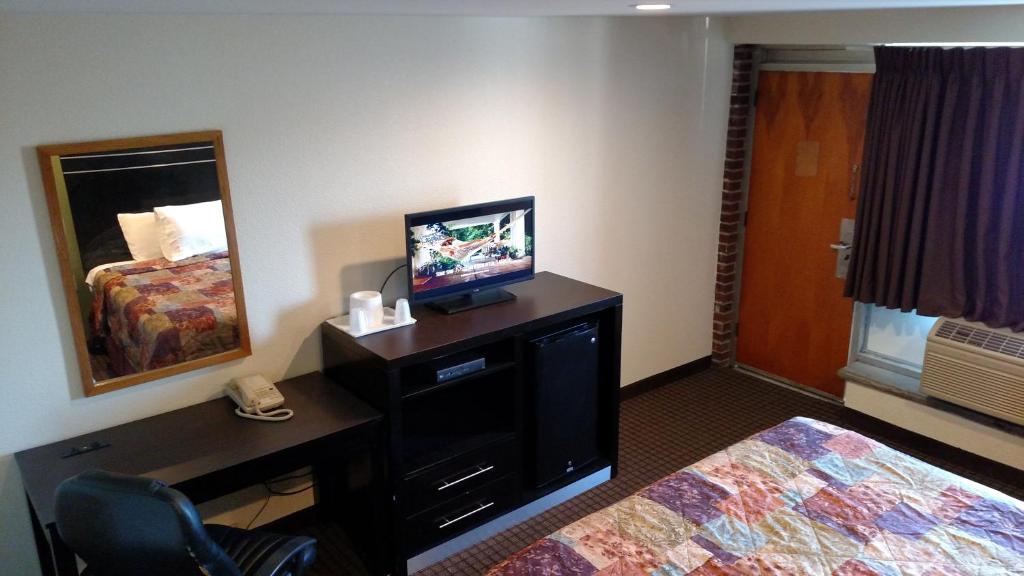 a hotel room with a television and a bed and a desk at Gene's Motel in Cinnaminson