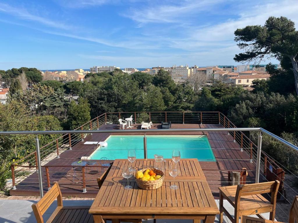 - une table en bois avec une corbeille de fruits sur une terrasse à côté de la piscine dans l'établissement Maison La Falaise avec piscine, à Narbonne-Plage