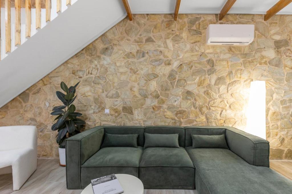 a living room with a green couch and a stone wall at Casa Woopi Torrevieja in Torrevieja