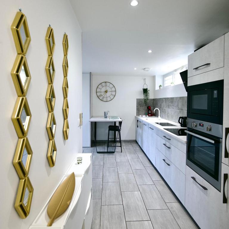 d'une cuisine avec des placards blancs et des touches dorées. dans l'établissement Saint-Étienne Bellevue Confort 1, à Saint-Étienne