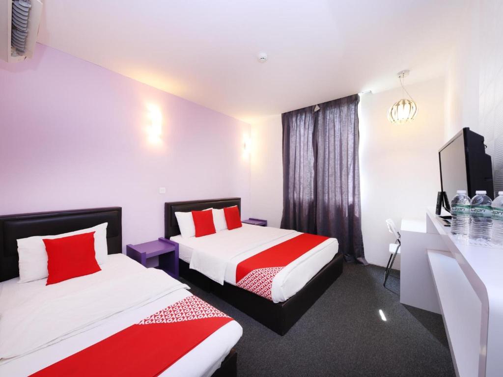 a hotel room with two beds with red pillows at Hotel O Marvelton Hotel in Butterworth