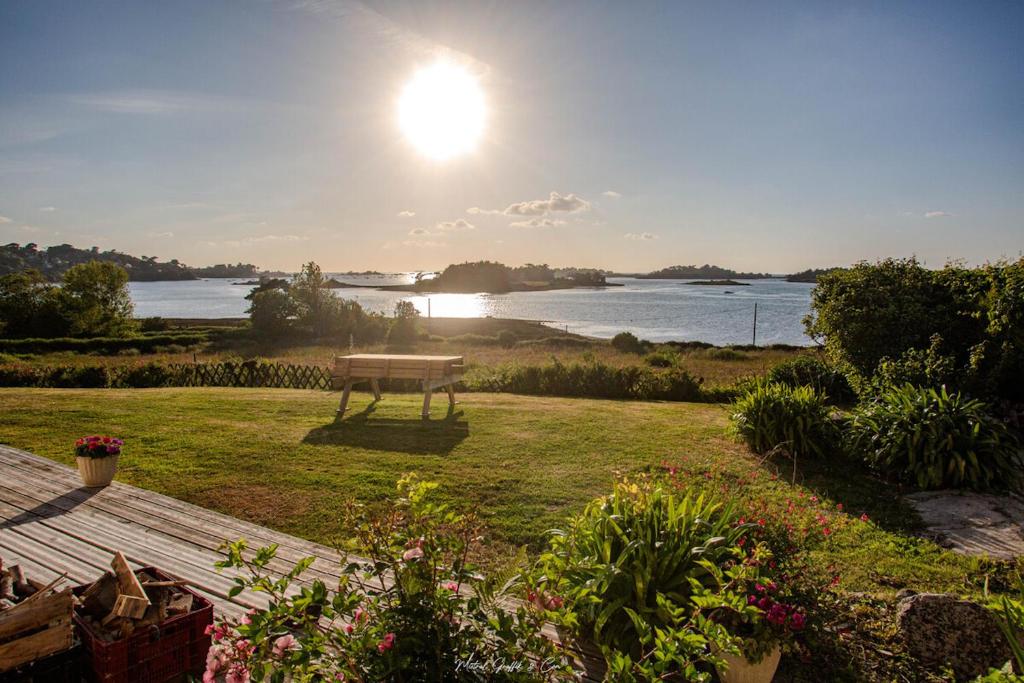 a bench in a field with a view of the water at Maison pour 7 - Superbe vue mer depuis le jardin in Penvénan
