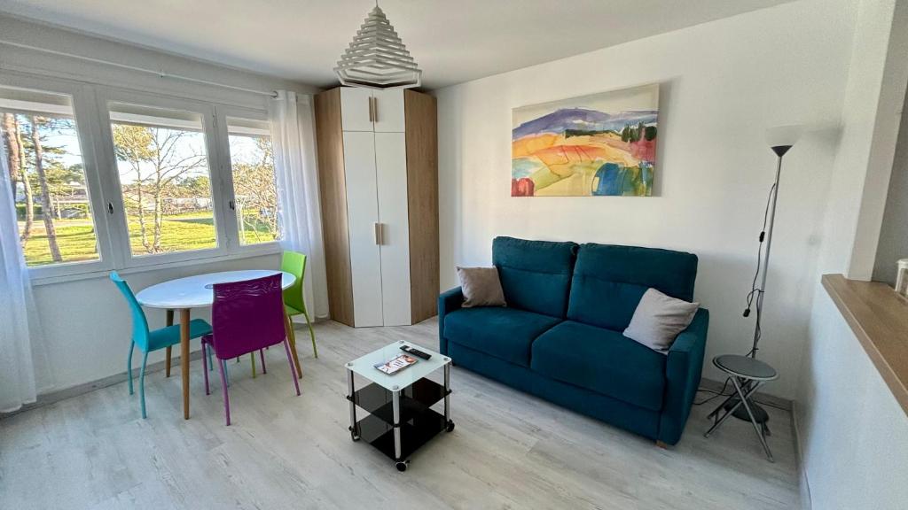 un salon avec un canapé bleu et une table dans l'établissement La Forêt 5, à Mimizan-Plage