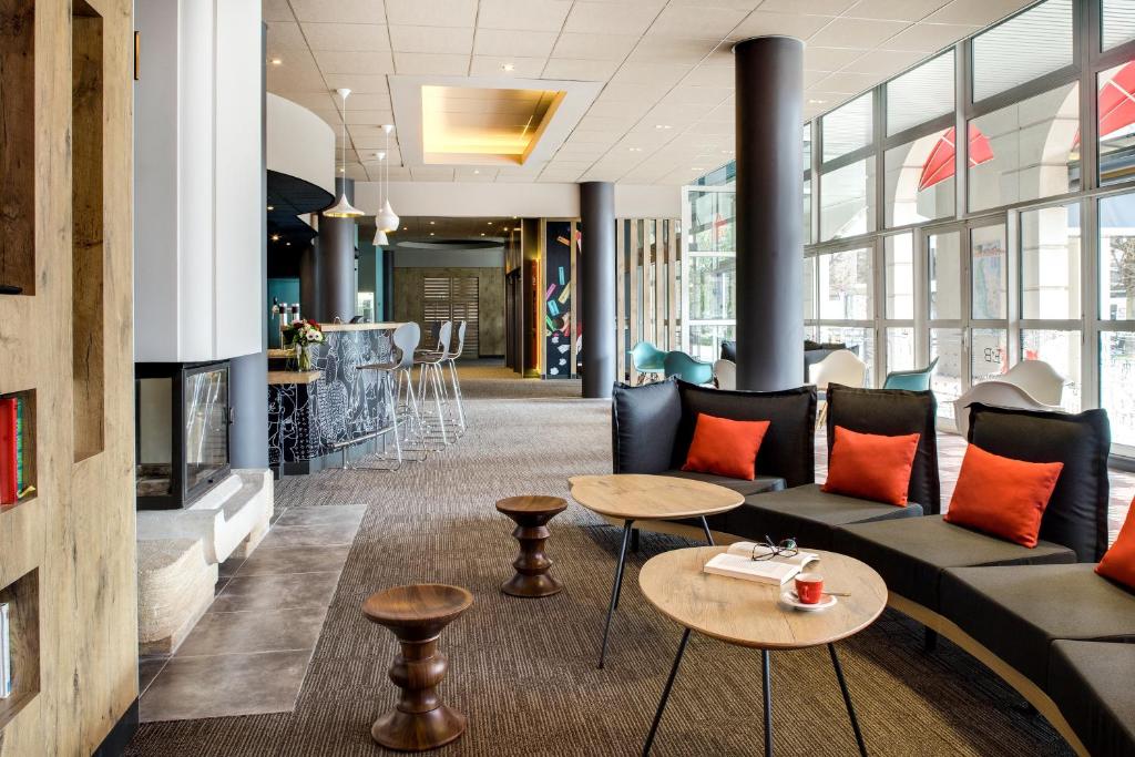 a lobby with a couch and tables and a bar at ibis Vichy in Vichy