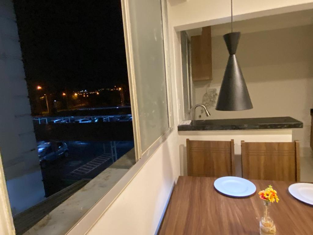 a kitchen with a table and a window with a view at Apartamento em frente ao novo shopping in Ribeirão Preto