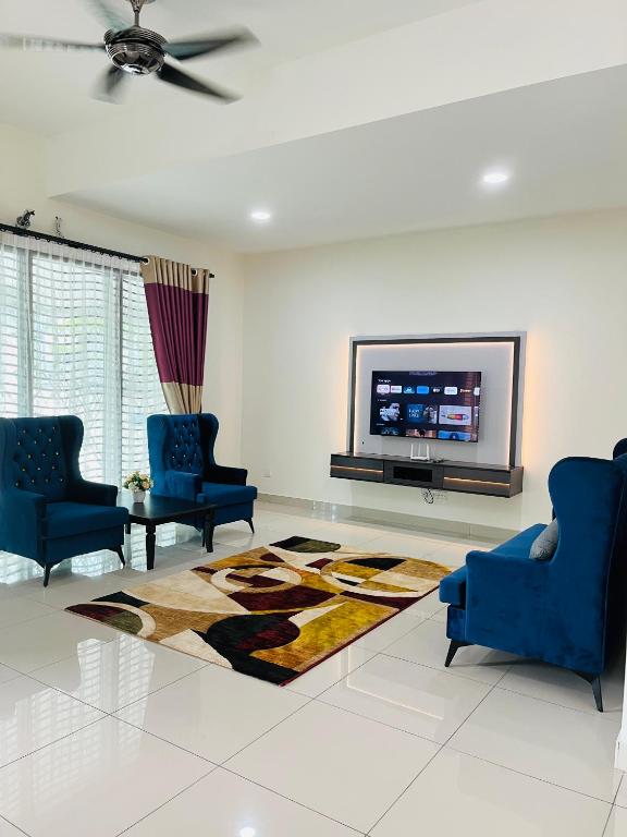 a living room with two blue chairs and a flat screen tv at Sofea Homestay Ipoh V2 in Ipoh