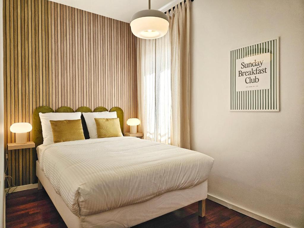 - une chambre dotée d'un grand lit avec des draps blancs et des oreillers en or dans l'établissement Ardoines Suite - Duke Housing, à Vitry-sur-Seine