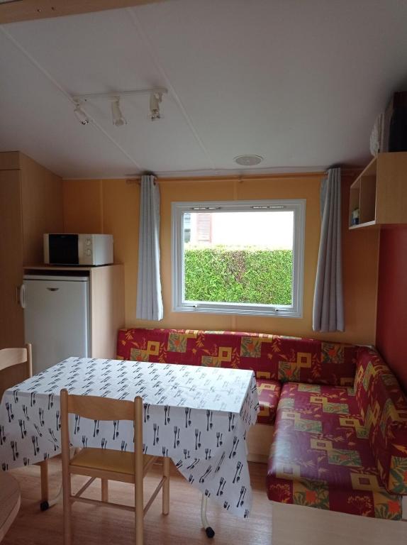 Cette chambre comprend une table, un canapé et une fenêtre. dans l'établissement Charming Mobile Home Campsite 3stars 40 min from Paris, à Saint-Chéron
