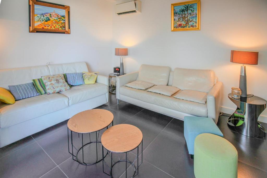un salon avec un canapé et deux tables dans l'établissement CHENES Lumineux Vue Mer Clim Confort Terrasses Parking, à Antibes
