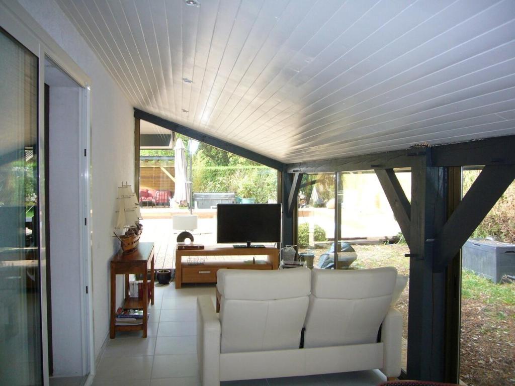 un salon avec un canapé blanc et une télévision dans l'établissement house with heated pool and jacuzzi, à Soorts-Hossegor