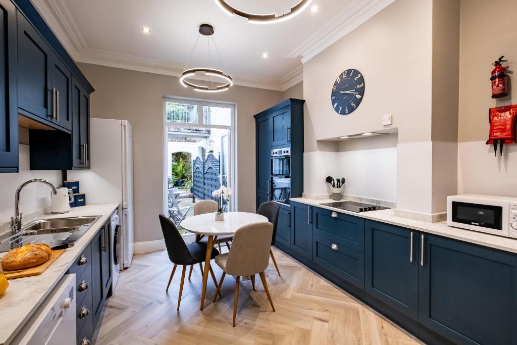 a kitchen with blue cabinets and a table with chairs at St Kitts Apartment in Filey