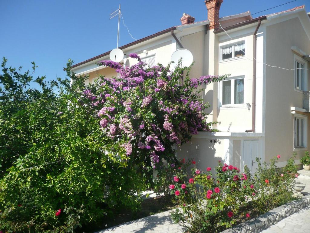 a white house with purple flowers in front of it at Apartment in Rab/Insel Rab 16488 in Mundanije