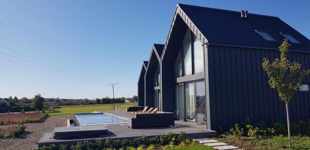a black house with a patio and a pool at Kameralna Domki in Bystrzyca Nowa
