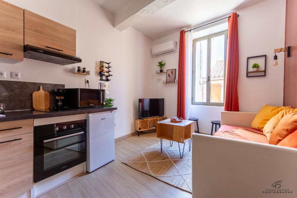 a kitchen and a living room with a couch at Le Carignan - 4 personnes - Proche des plages in Lapalme
