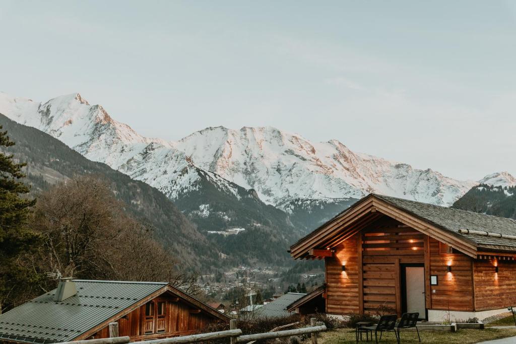 a log cabin with mountains in the background at Hôtel Restaurant La Ferme de Cupelin in Saint-Gervais-les-Bains