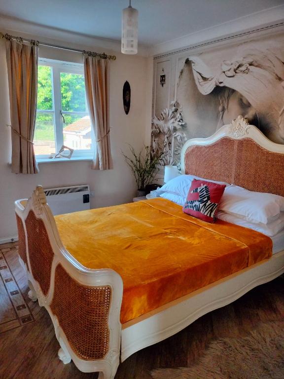 a bedroom with a large bed with an orange bedspread at Canalside Chic Your London Escape Starts Here WIFI and Airport Transfers in Hemel Hempstead