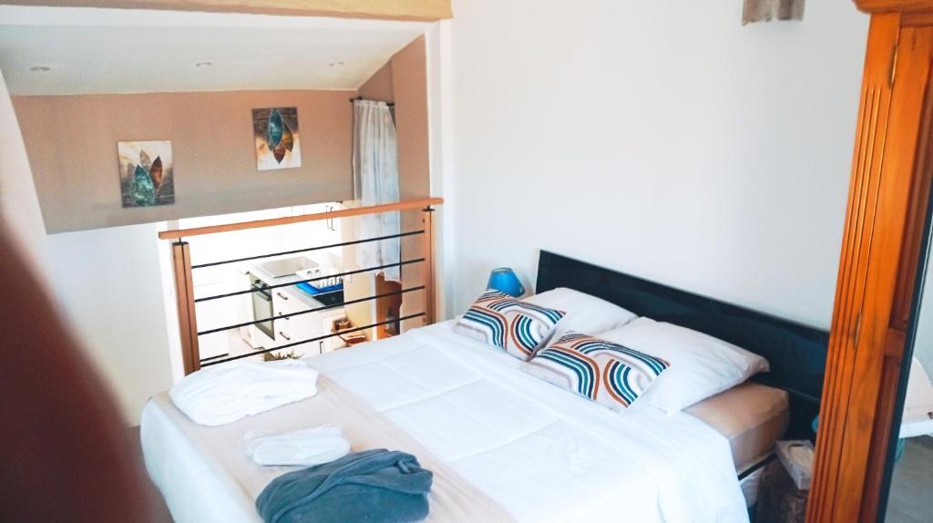 un lit avec des draps blancs et des oreillers dans une chambre dans l'établissement BANDOL TYPE 2 AVEC TERRASSE et PARKING, à Bandol