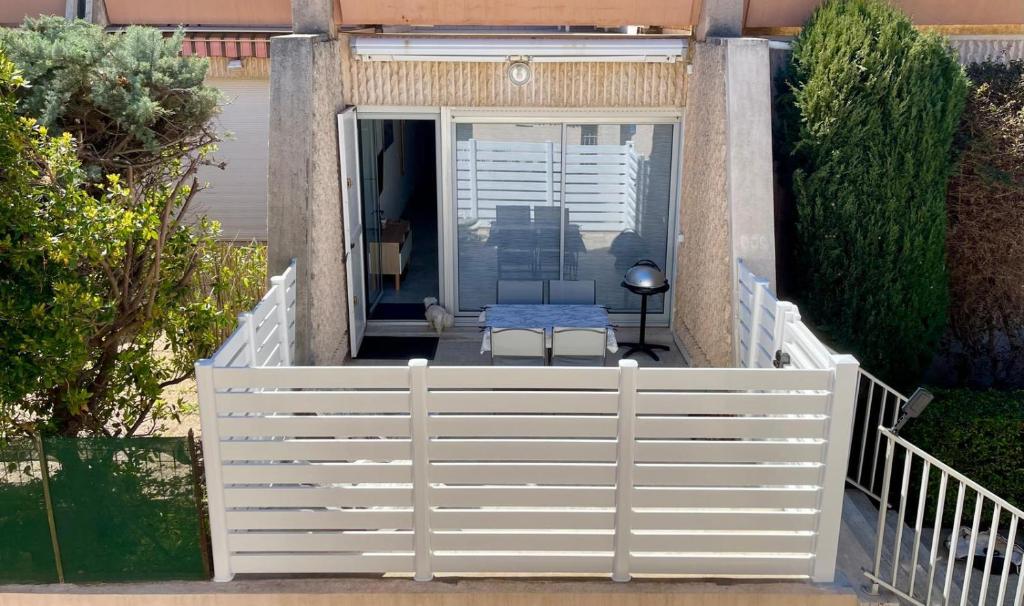 une clôture blanche avec une table sur une terrasse dans l'établissement Appartement Terrasse, centre-ville, 5 min de la plage, à Cavalaire-sur-Mer
