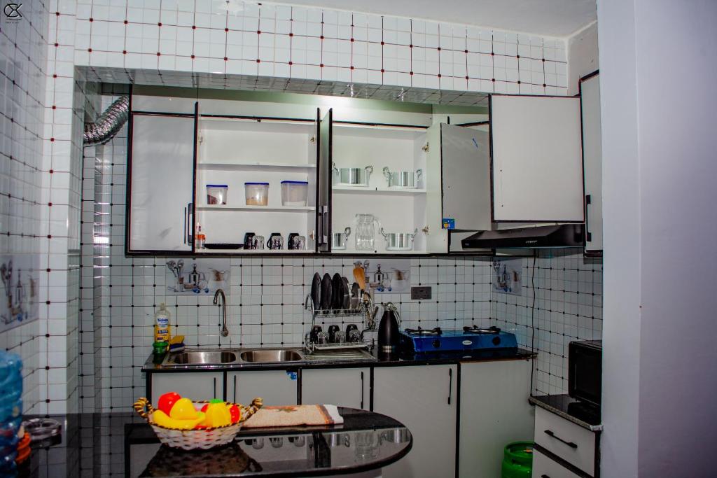 a kitchen with white cabinets and a bowl of fruit on a table at Esidai Homes in Narok