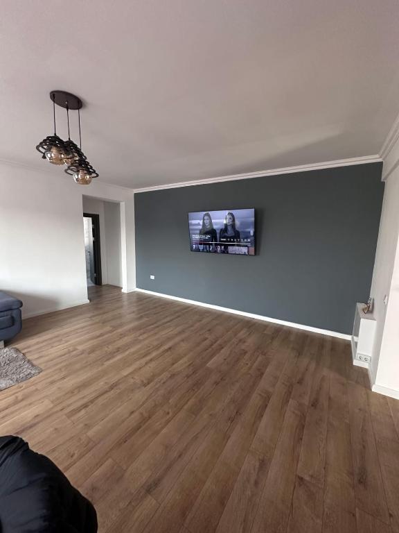an empty living room with a flat screen tv on a wall at Apartament Icas in Dej