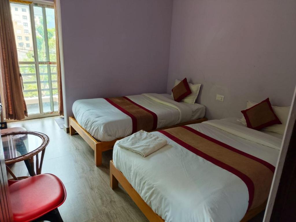 una camera con due letti e una sedia e una finestra di Hotel sunrise heaven a Pokhara
