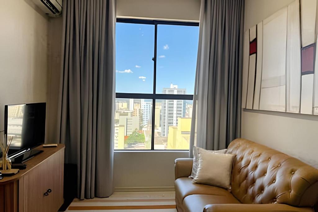 a living room with a couch and a large window at Flat centro de Londrina - Vista incrível in Londrina