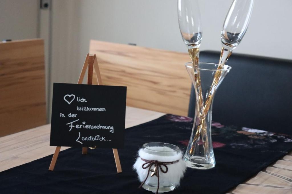 a table with two wine glasses and a sign on it at Ferienwohnung Landblick in Pirmasens