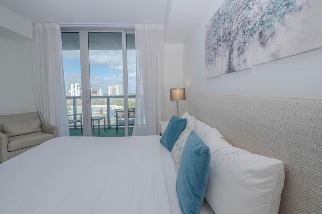 Una habitación blanca con una cama y una ventana en Steps from the beach 2B 2B Pool, Gym, and More, en Hallandale Beach