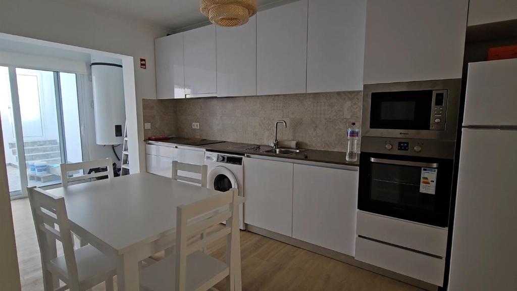 una cucina con mobili bianchi, un tavolo e un microonde di BoaVista House 1 a Maia