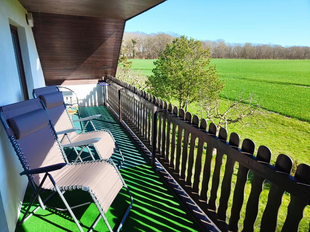 a row of chairs sitting on a porch with a field at Aparthotel Schafshorn in Schaprode