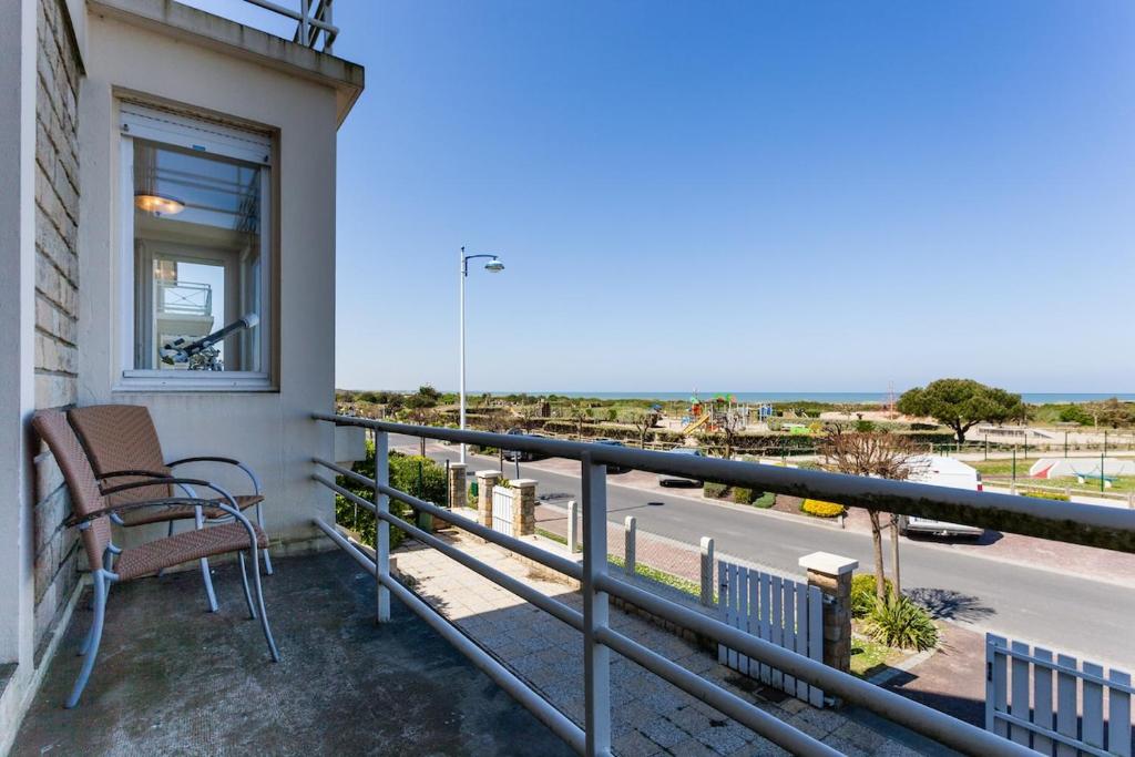 un balcon avec une chaise et une vue sur une rue dans l'établissement Superb beach-front family house, à Merville-Franceville-Plage