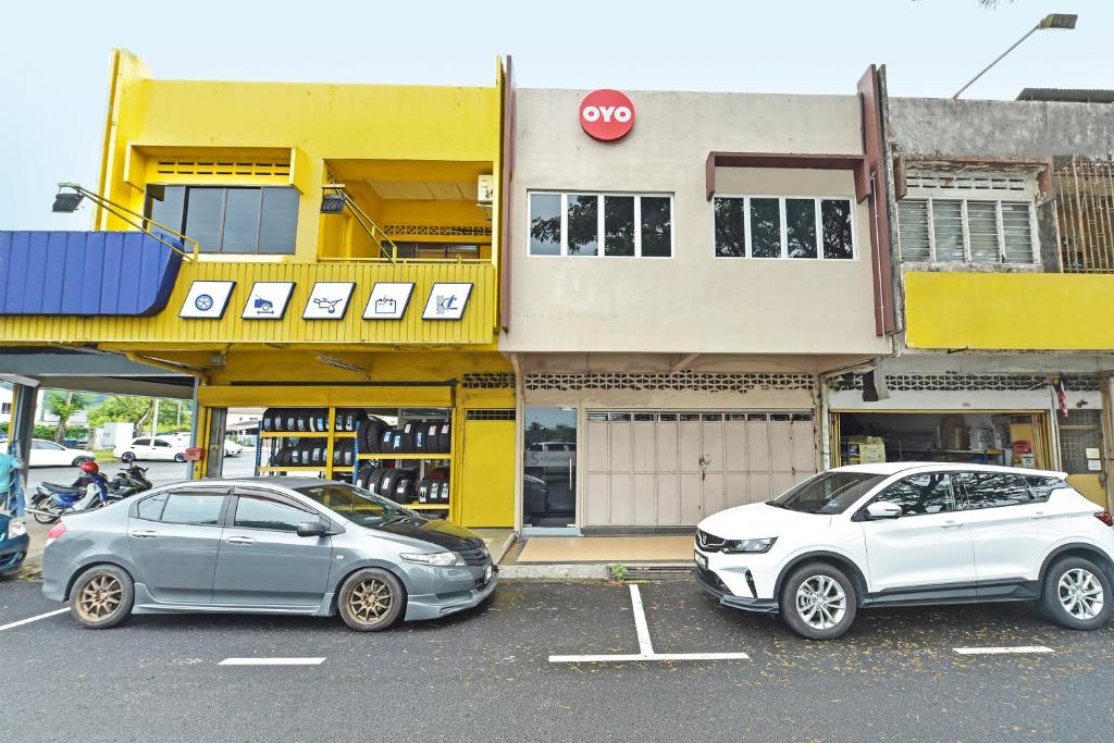 due auto parcheggiate in un parcheggio di fronte a un edificio di Hotel O S Homestay a Kuantan