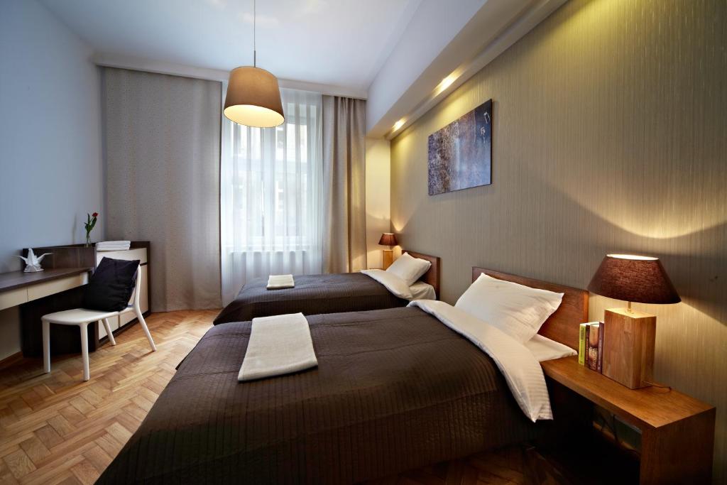 クラクフにあるMOKO Apartmentsのベッド2台とデスクが備わるホテルルームです。