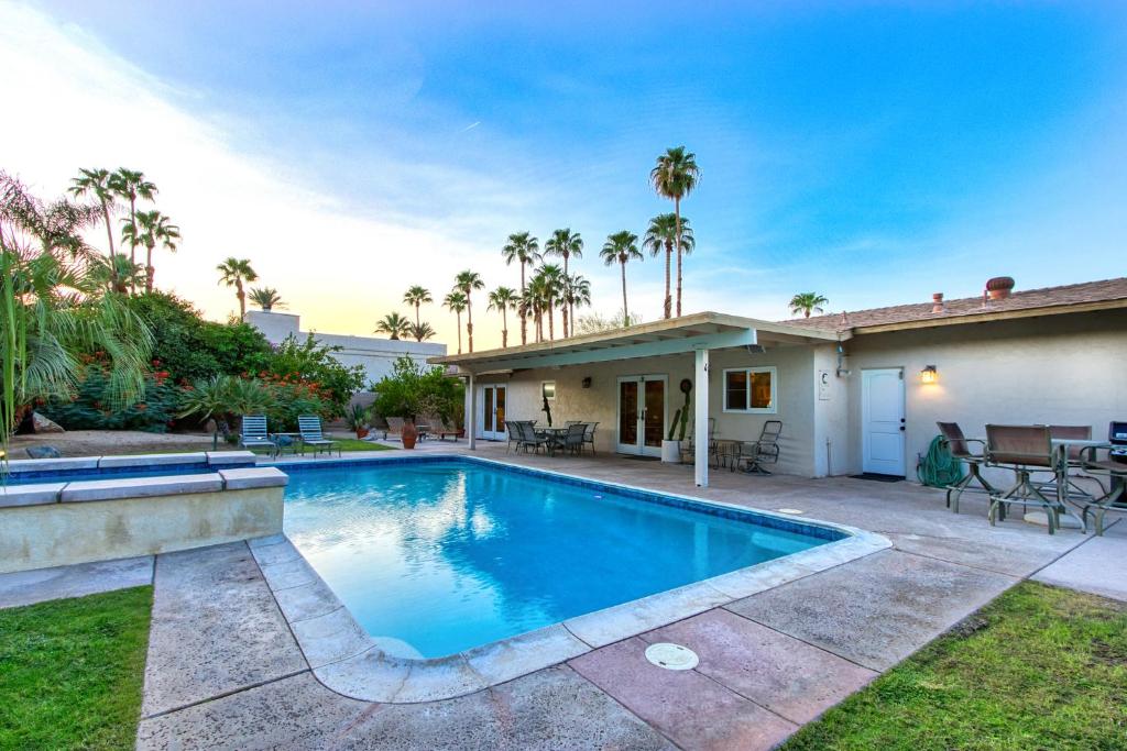 a swimming pool in front of a house with palm trees at Vintage Paseo Getaway in Palm Desert