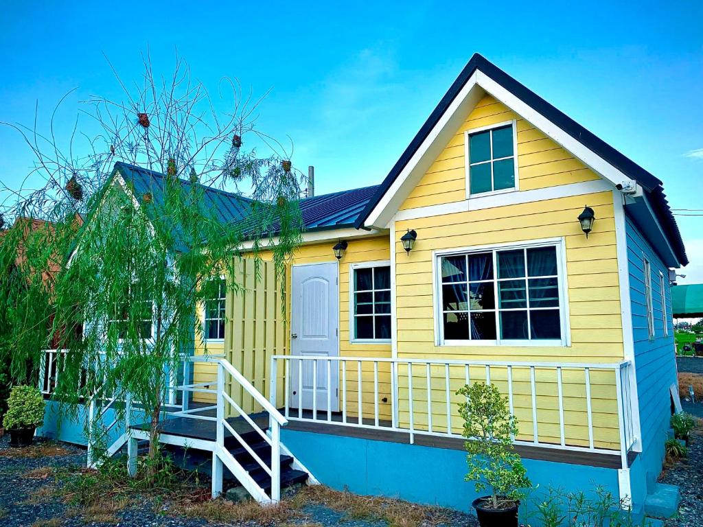 une maison jaune et bleue avec une terrasse couverte dans l'établissement Chai Na Resort, à Bangkok
