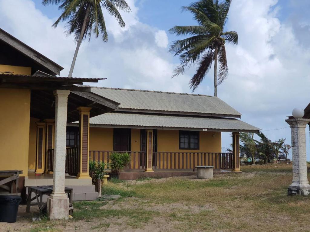 a house with a palm tree in front of it at Hotel O Bayu Chalet in Kota Bharu