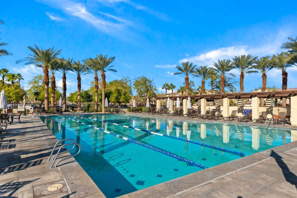 a large swimming pool with palm trees in the background at Spanish Walk Villa - PD condo near acrisure in Palm Desert
