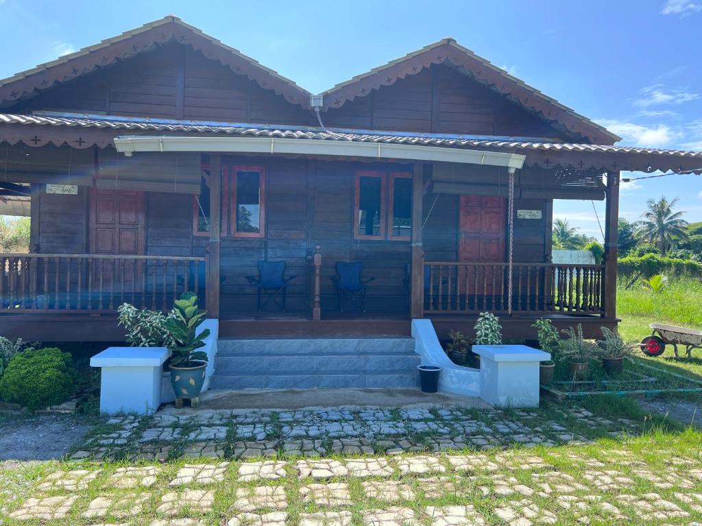 a wooden house with a porch at Hotel O Sri Ayu Inn in Kampung Gurun