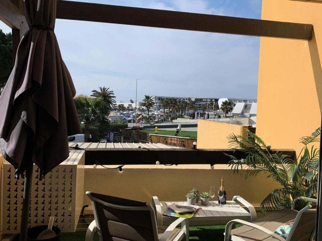 un patio avec un parasol, une table et des chaises dans l'établissement Résidence Port Nature Colline 5 - Studio 2 personnes Port Nature Colline 5 MAE-5291, au Cap d'Agde