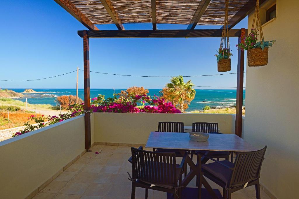 ein Tisch und Stühle auf einem Balkon mit Blick auf das Meer in der Unterkunft Villa Sunrise by the Sea in Kiotari