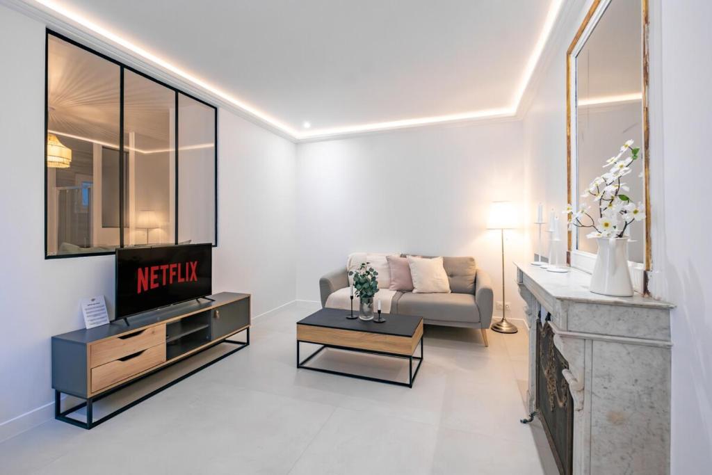 un salon avec un canapé et une télévision dans l'établissement Haussmann Apartment - Champs-Élysées, à Paris