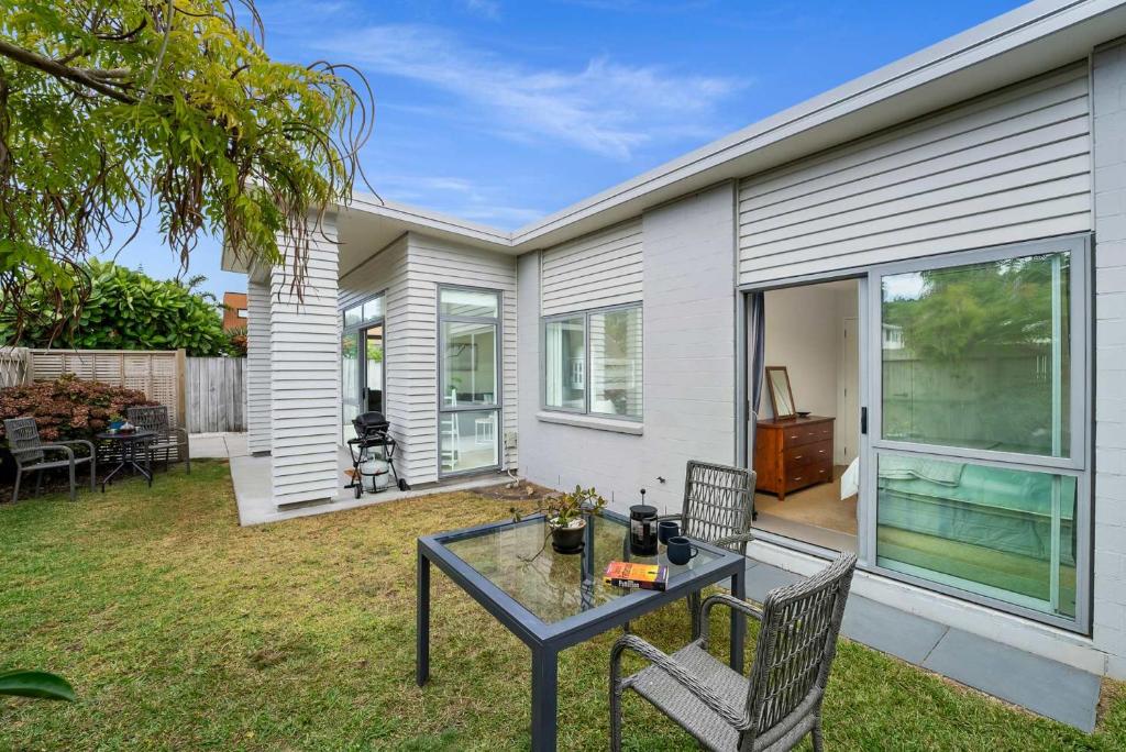 un patio con tavolo e sedie di fronte a una casa di Sunny Seaside Retreat - Papamoa Beach a Papamoa