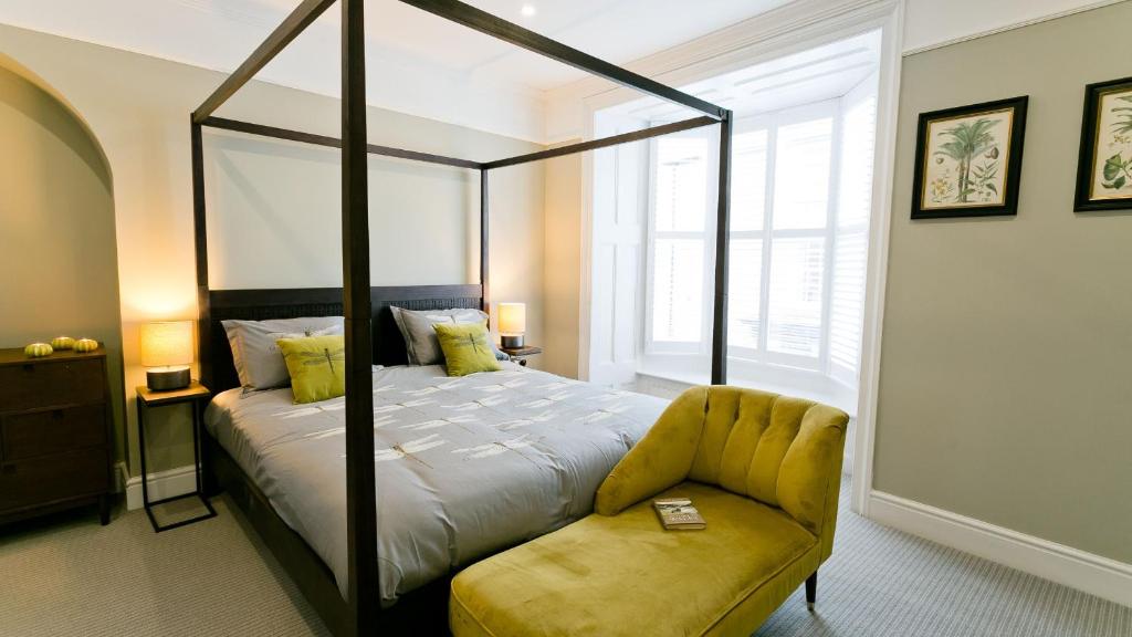 a bedroom with a canopy bed and a yellow couch at Beau Townhouse in Beaumaris