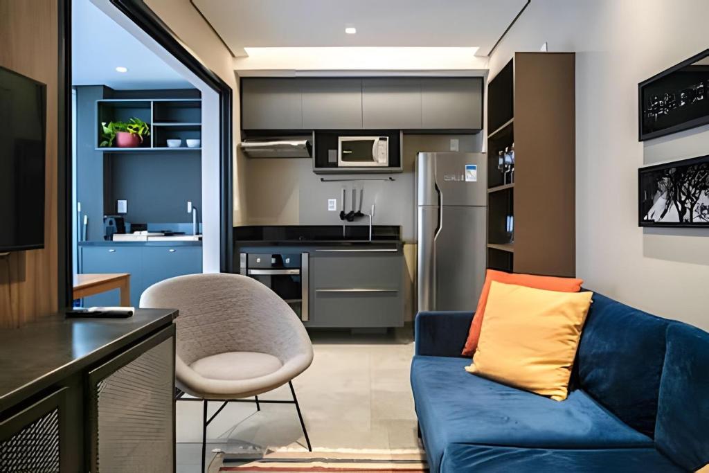 a living room with a blue couch and a kitchen at Occa Stay Cobogó - A115 in Sao Paulo