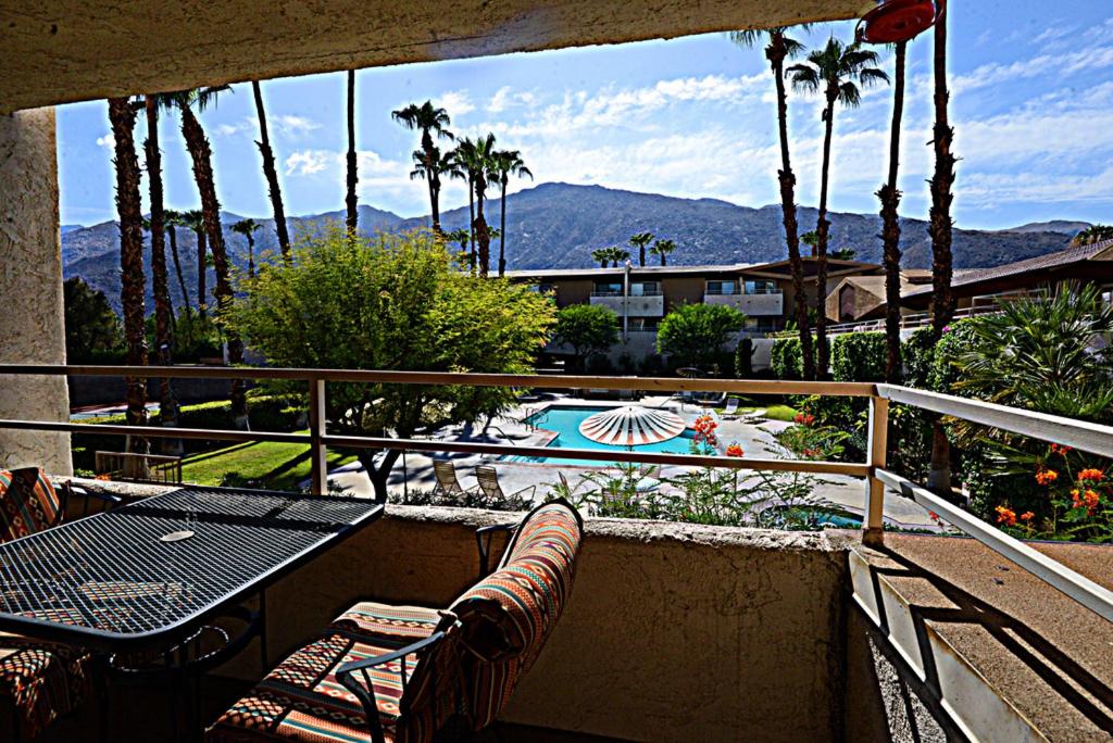 a balcony with a table and chairs and a swimming pool at Biarritz Mirage - 1BR Downtown Condo in Palm Springs