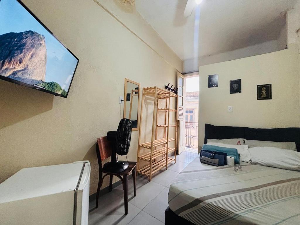 een slaapkamer met twee bedden en een tv aan de muur bij Pequena Suíte Individual 304 in Rio de Janeiro