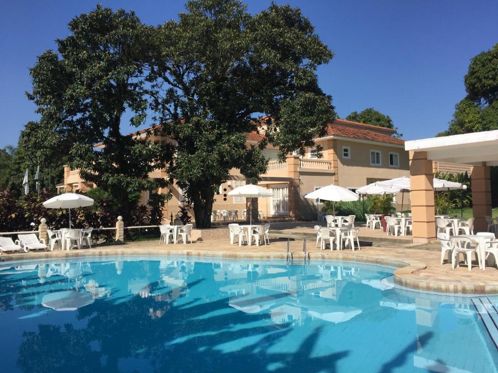 a swimming pool with white chairs and umbrellas at Hotel La Ponsa Itatiaia in Itatiaia