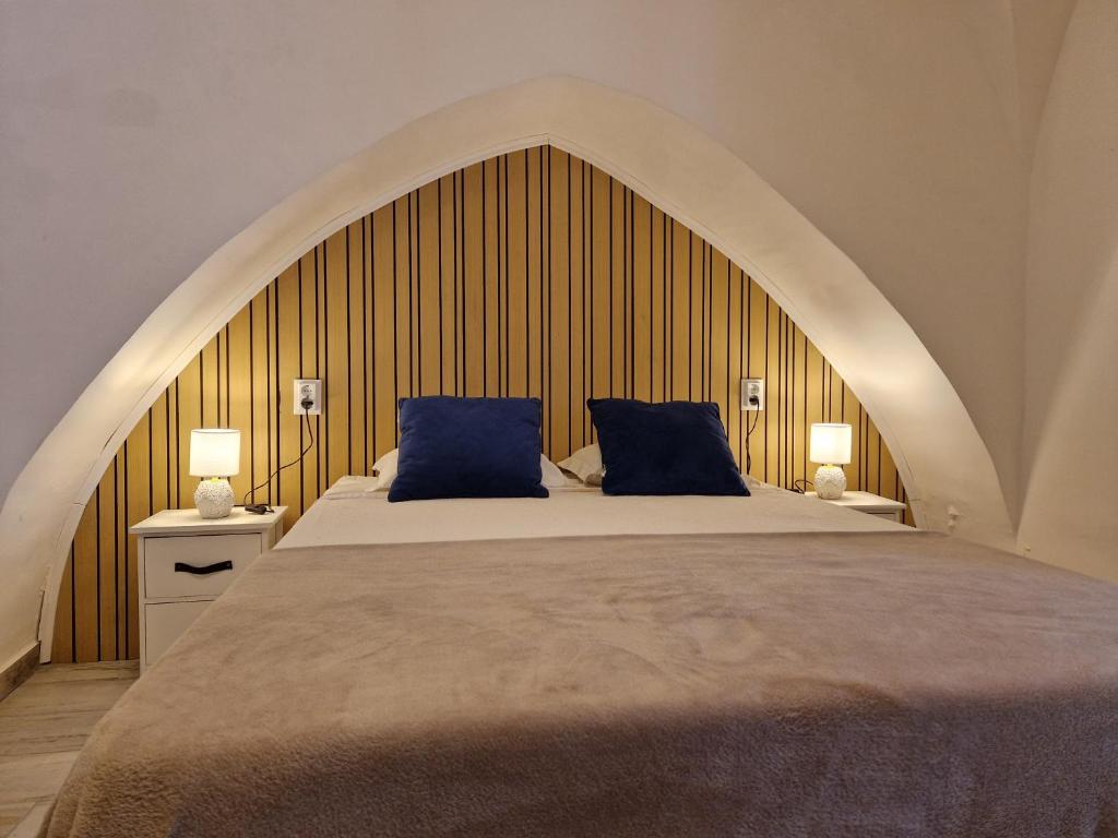 a bedroom with a large bed with two blue pillows at Casa da Judiaria in Évora